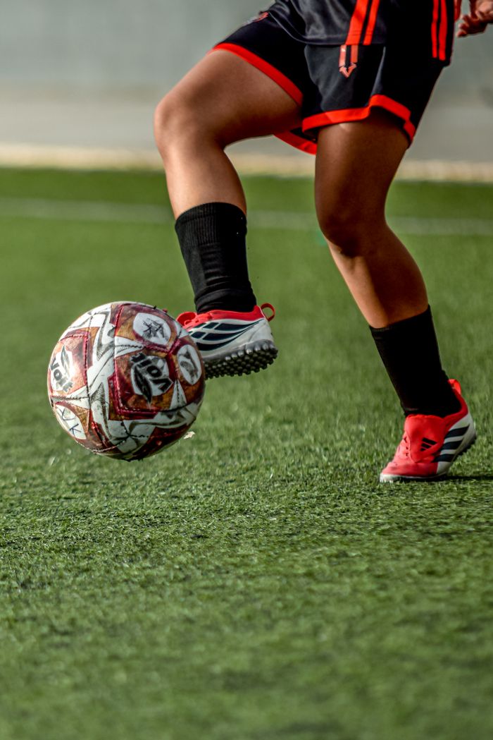 Close-up of a soccer player skillfully controlling a ball on a field.