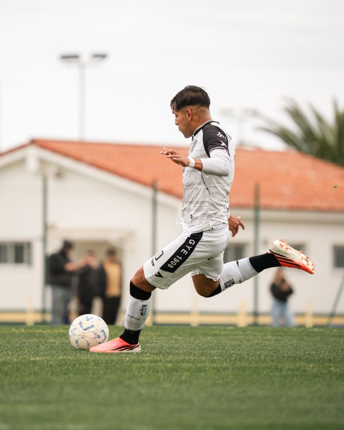 Soccer player in action kicking a ball during a daytime outdoor match.
