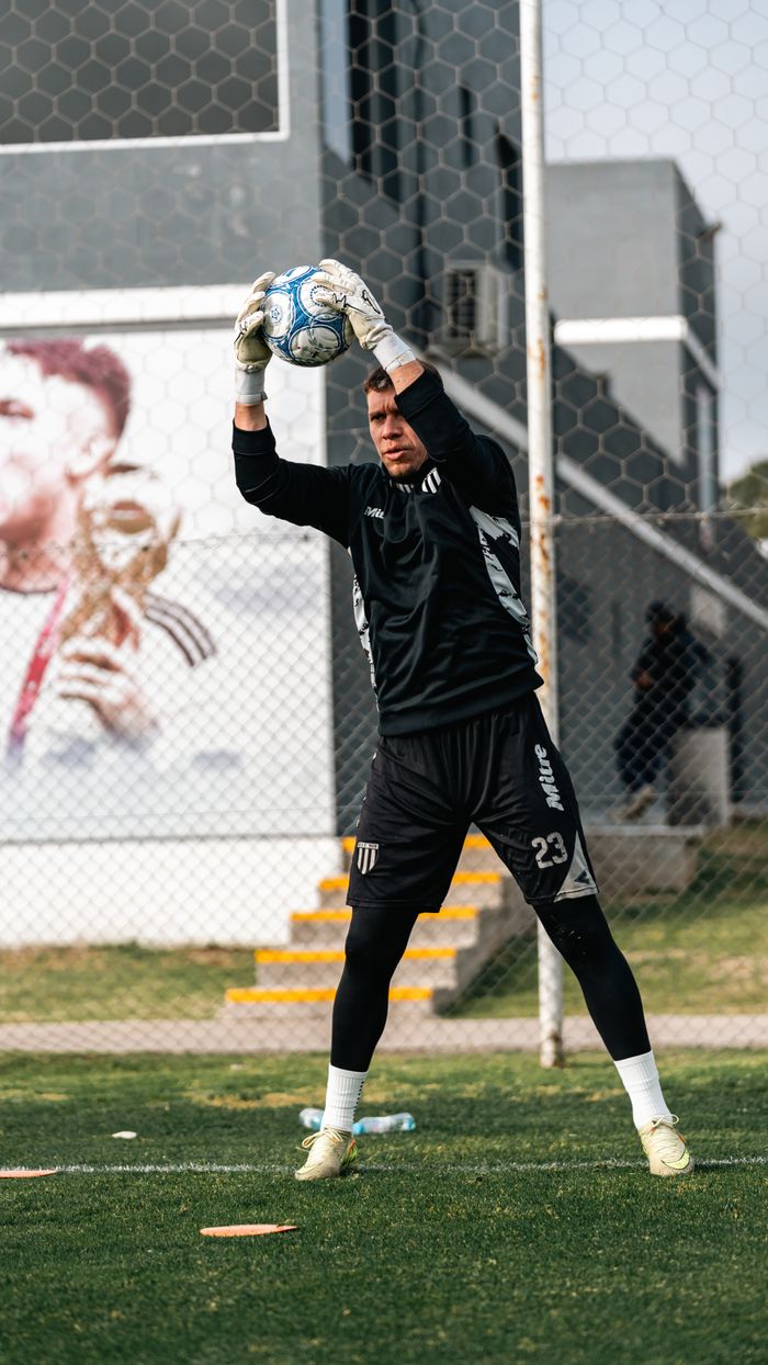 Soccer goalkeeper practicing catching drills on urban sports ground.