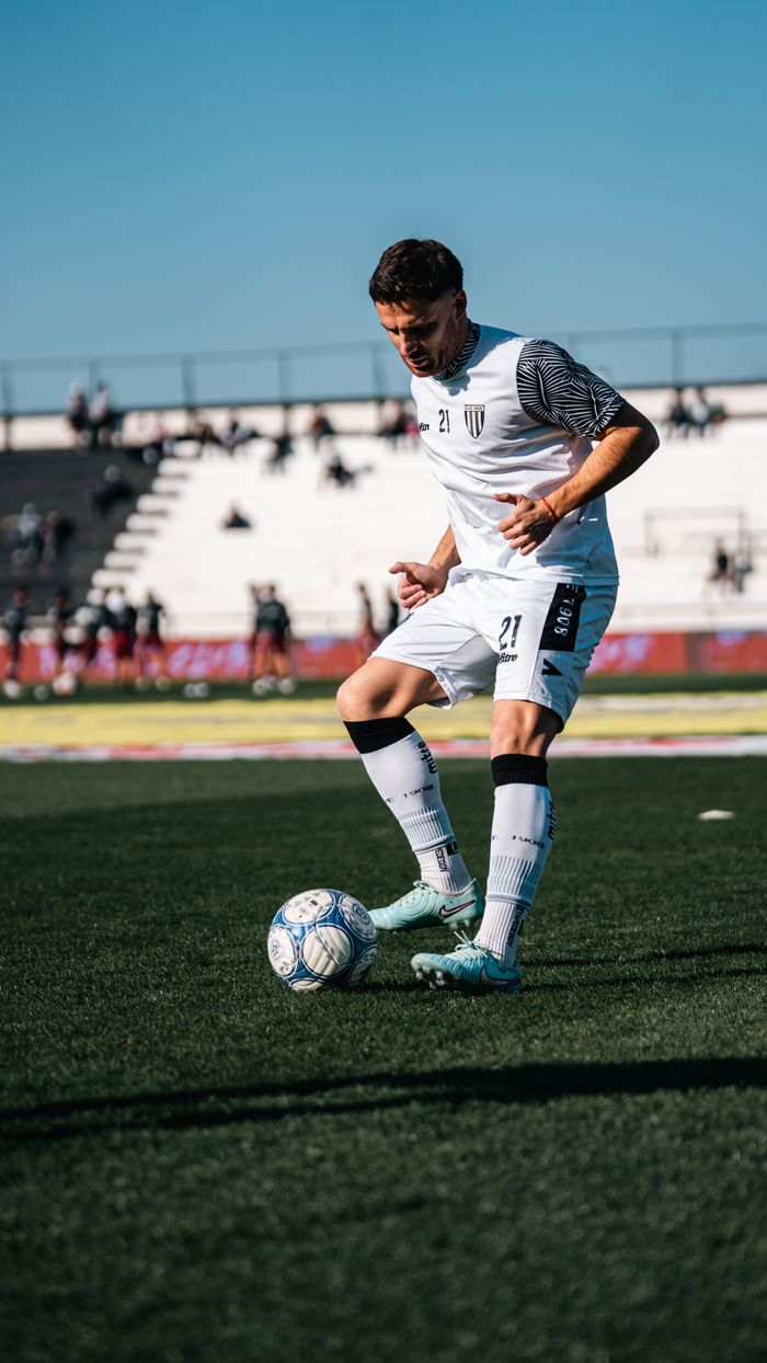 services-04 Soccer player in white jersey dribbling during the day on a professional field, showcasing athletic skill.